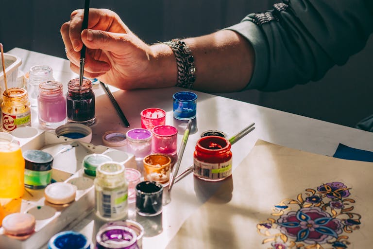 An artist's hand painting with colorful acrylics, showcasing creativity and vibrant art.