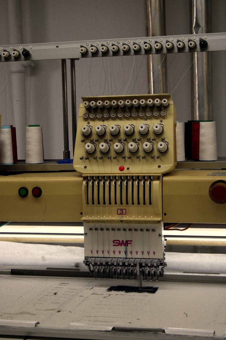 Close-up of a modern industrial embroidery machine with spools of thread for textile production.